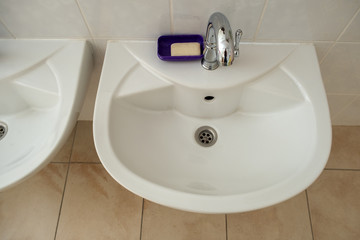 White ceramic washing basins with shiny stainless steel water tap.