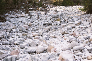 A lot of stones in the snow. Difficult route in the mountains