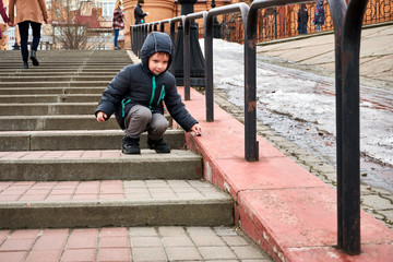 A little boy plays on the concrete stairs in the fall.