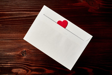 Naklejka na ściany i meble White envelope with a heart on a dark wooden background. Love letter, valentine concept.