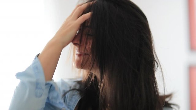 Playful Brunette woman messing hair with hands feeling free and smiling to camera