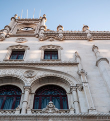 Obraz premium Lisbon train station entrance & blue sky, showing arched windows, clock & beautiful masonry. 