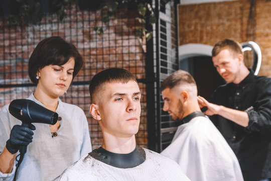 Hairdressers cut their clients in barbershop. Advertising and barber shop concept