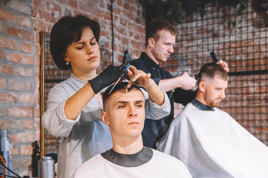 Hairdressers cut their clients in barbershop. Advertising and barber shop concept