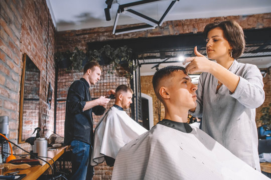 Hairdressers cut their clients in barbershop. Advertising and barber shop concept