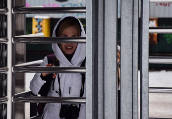 Woman in a white jacket behind metal turnstiles
