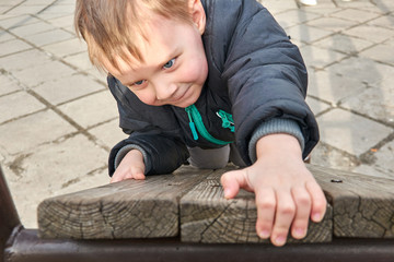 Naklejka premium little boy is climbing on a wooden board.