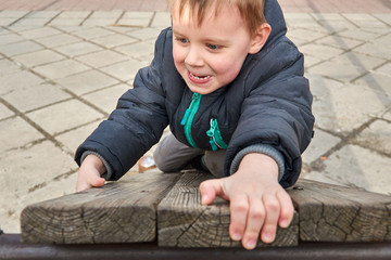 Naklejka premium little boy is climbing on a wooden board.