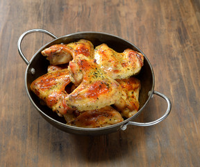 grilled chicken wings in bowl on wooden background