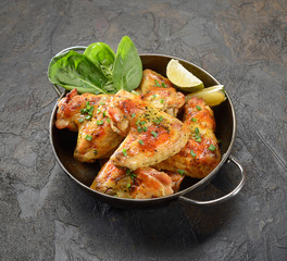 grilled chicken wings with spinach and lime in a bowl on a dark background