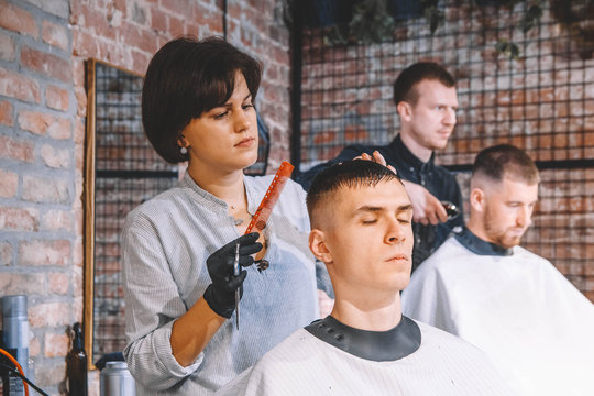 Hairdressers cut their clients in barbershop. Advertising and barber shop concept