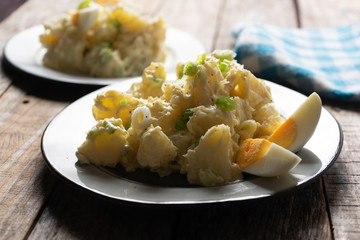 Potato salad with egg and mayonnaise on wooden background