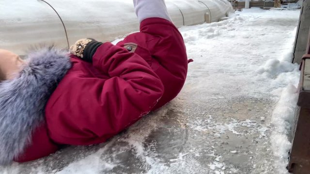 Risk of accidents in winter - A woman slipping on a snow slippery road during freezing cold Russian winter. Close up 4k slow motion video