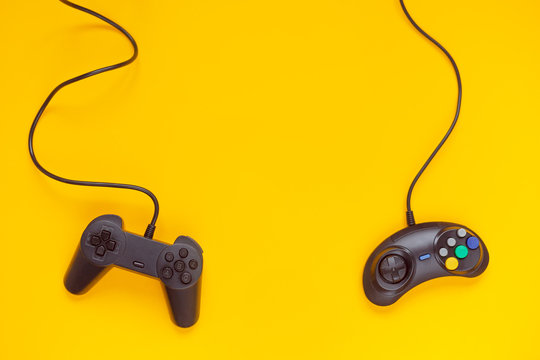 Two wired gamepads or video game controllers on yellow background. Top view, flat lay. Gaming, console industry