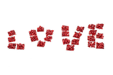 Word love made from pomegranate seeds on a white background