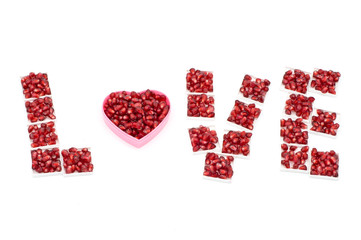 Word love and heart made from pomegranate seeds on an isolated background background