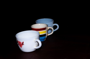 There are three cups arranged one by one on black background