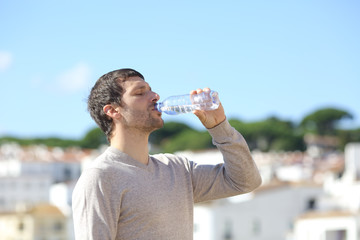 Profile of an adult man drinking bottled water in a town