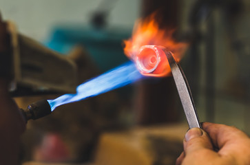 Jeweler at work with a propane burner in a jewelry workshop. Fire close up.
