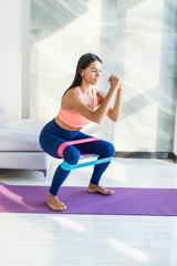 Obraz premium Young woman during her fitness workout at home with rubber resistance band
