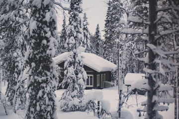 Fototapeta premium A cozy wooden cabin cottage chalet house covered in snow near ski resort in winter with the lights turn on