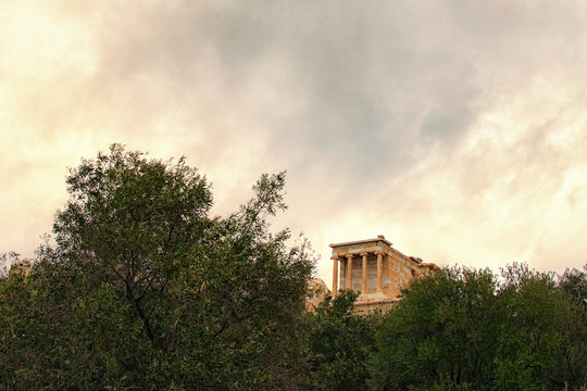 Beautiful landscape photo of Temple of Athena Nike. Dedicated to the goddess Athena Nike. Built around 420 BC. Tree Leaves Border. Natural Frame. Stormy sky and gloomy clouds. Athens Greece