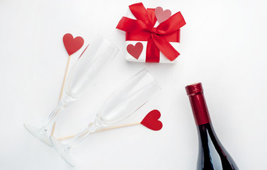 composition for  holy day  Valentine red wine and glasses, gift and hearts made of paper on a white background with copy space for your text