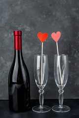 a bottle of red wine and two glasses, stone background for Valentines Day.