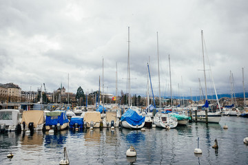 Fototapeta na wymiar Beautiful yachts at the water port in European town, travel, tourism and vacation concept. Photography with white boats and the city lake on cloudy sky background.
