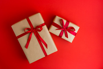 Two Brown gift boxes with red ribbons on Red background. Flat lay style. Gift for Christmas, holiday or a birthday.