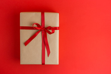 Brown gift box with red ribbons on Red background. Flat lay style. Gift for Christmas, holiday or a birthday.