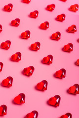 Fototapeta na wymiar Heart shaped red crystals pattern on pink background. Vertical image Valentine's Day.