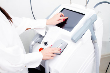 Apparatus for hair removal close-up. The doctor sets the parameters for hair removal on the epilator.