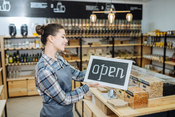 Pretty worker showing open sign at the bakery