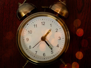 Vintage alarm clock on a dark background. Round clock in multi-colored lights. Desktop mechanical...