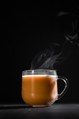  hot cocoa with milk in a transparent mug with steam on a black background with a place for inscription
