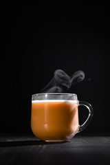  hot cocoa with milk in a transparent mug with steam on a black background with a place for inscription