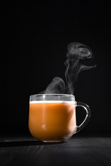  hot cocoa with milk in a transparent mug with steam on a black background with a place for inscription