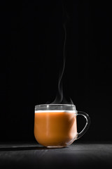  hot cocoa with milk in a transparent mug with steam on a black background with a place for inscription
