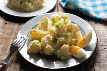 Potato salad with egg and mayonnaise on wooden background
