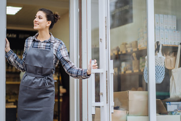Beautiful asian woman store owner with standing in the doorway of her coffee shop looking at camera...