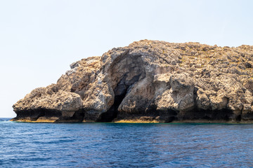 Fototapeta na wymiar View from a motor boat on the mediterranean sea at the rocky coastline near Lindos on the eastside of Greek island Rhodes