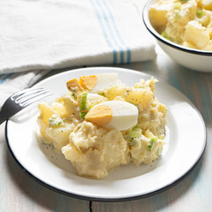 Potato salad with egg and mayonnaise on wooden background