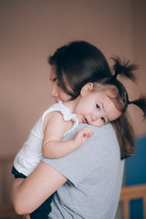 Young mother holding her little child girl. Daughter sleeping on mothers shoulder, care and love, soft focus.