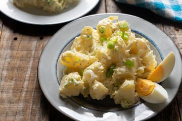 Potato salad with egg and mayonnaise on wooden background