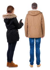 Back view of couple in winter jacket photographed on a mobile phone in winter jacket.
