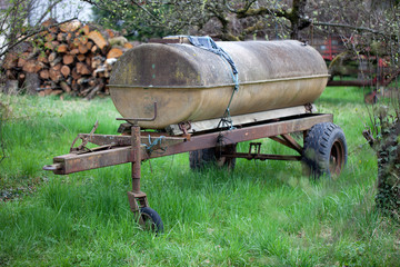 Agricultural old rusty trailer with a water tank on it