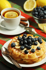 Belgian waffles with blueberry and a cup of tea with lemon	