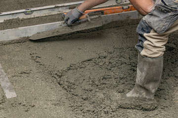 Floor screed is processed in the apartment. The worker performs a sand-cement floor screed.