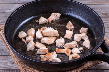Chopped chicken fillet fried on frying pan with raw meat